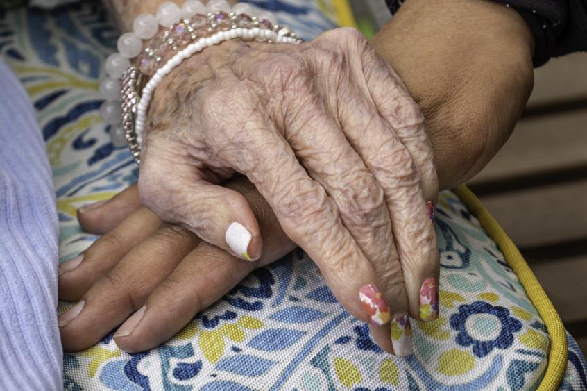 Close of of ASQ Caregiver holding hand of elderly patient