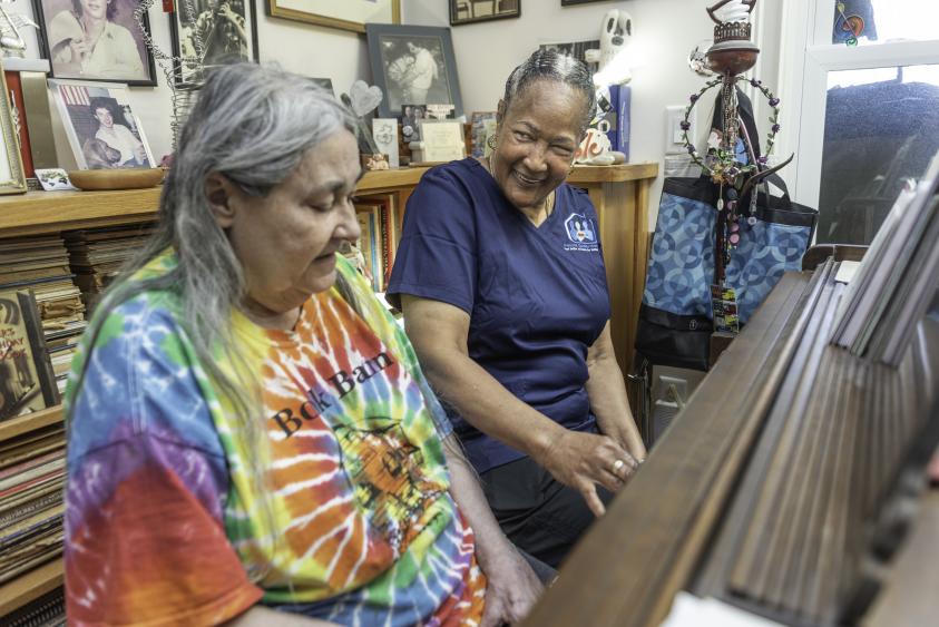 ASQ Homecare caregiver and patient siting next to a wooden piano